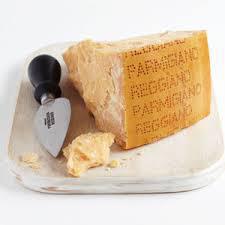 Wedge of Parmigiano Reggiano cheese on a plate with a cheese knife.