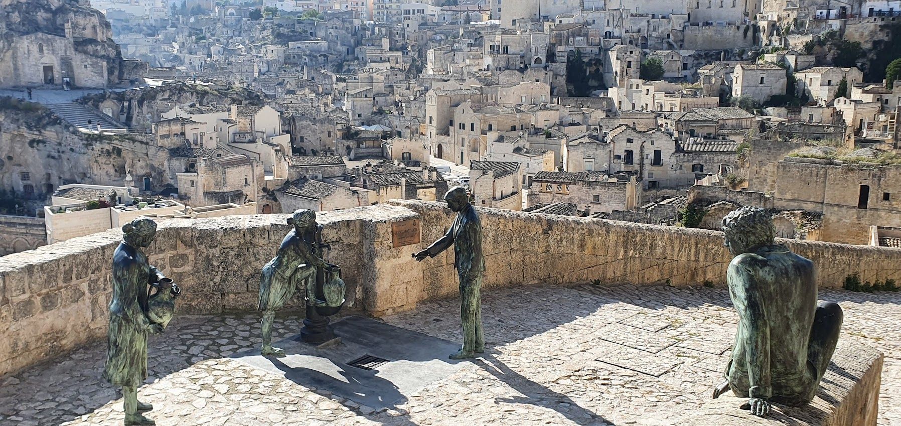 A group of statues standing next to each other on a ledge overlooking a city.