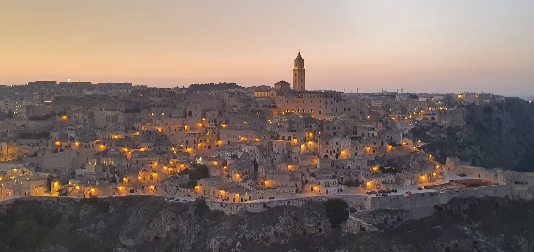 An aerial view of a city at sunset with a clock tower in the distance.