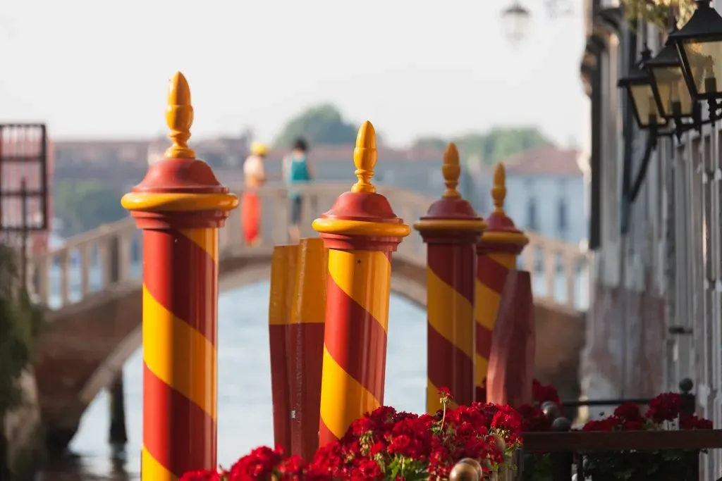 Colorful striped mooring poles by a canal in Venice.