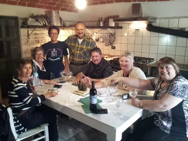 Group gathered around a table in a kitchen, displaying a truffle and wine bottle.