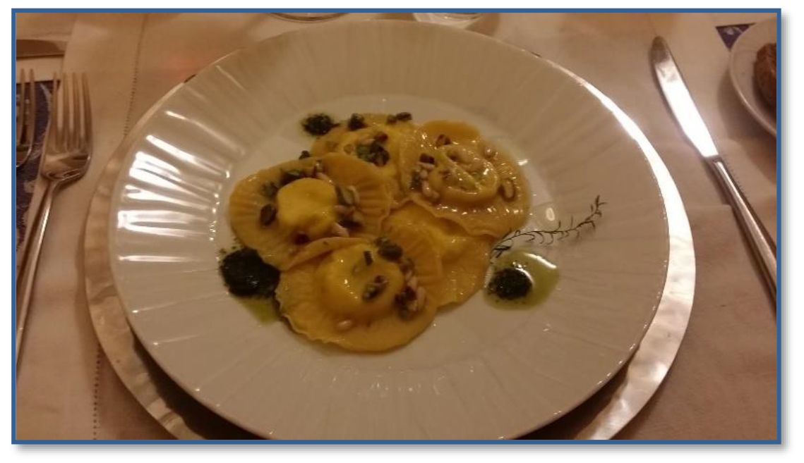 A white plate topped with ravioli on a table with silverware