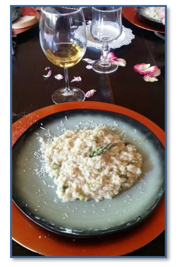 Asparagus risotto garnished with grated cheese, served with a glass of white wine.