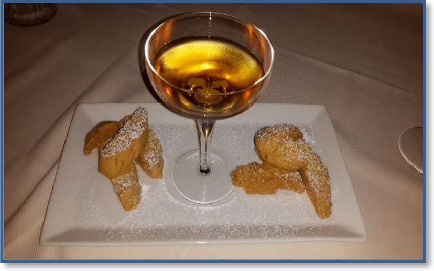 A glass of wine next to a plate of cookies