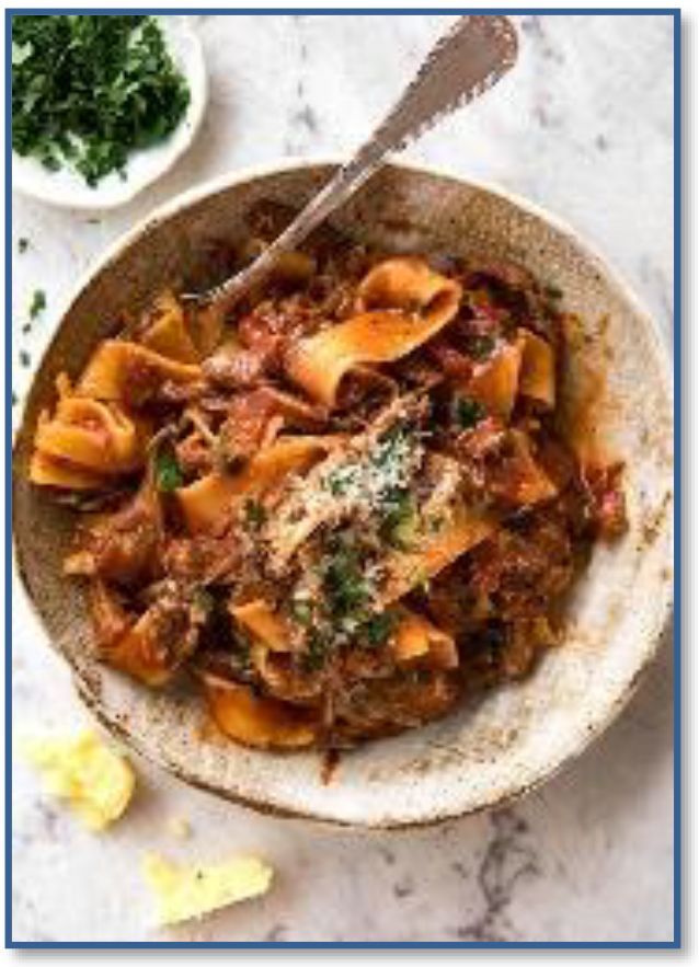 A bowl of pasta with a spoon in it on a table.