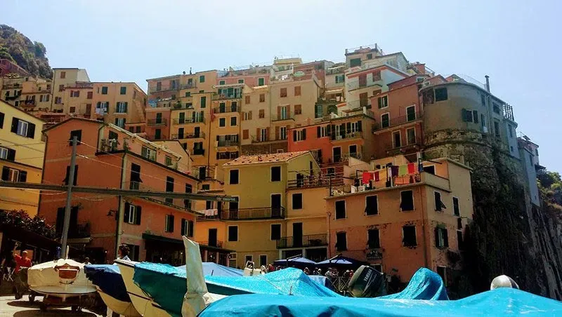Colorful cliffside buildings in Riomaggiore, Cinque Terre, with boats docked in the foreground.