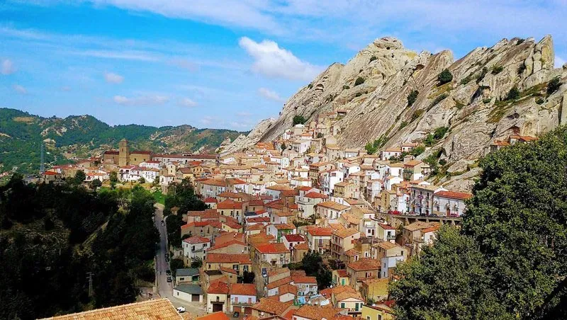 Cluster of terracotta-roofed houses built into the rocky cliffs of Castelmezzano in southern Italy.