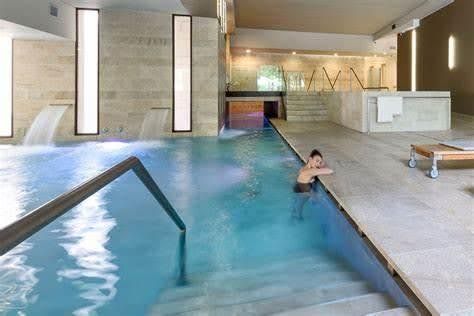 Indoor spa pool with cascading water features and a person relaxing by the steps