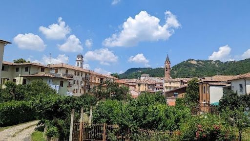 Scenic hillside village with terracotta rooftops, church towers, and lush greenery.