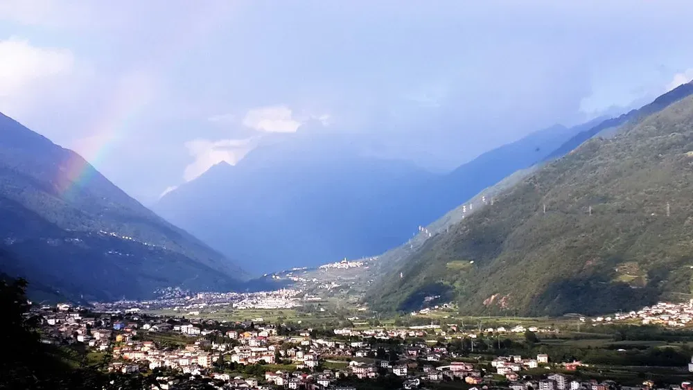 Overhead view of a mountain valley town in Italy, with scattered buildings.
