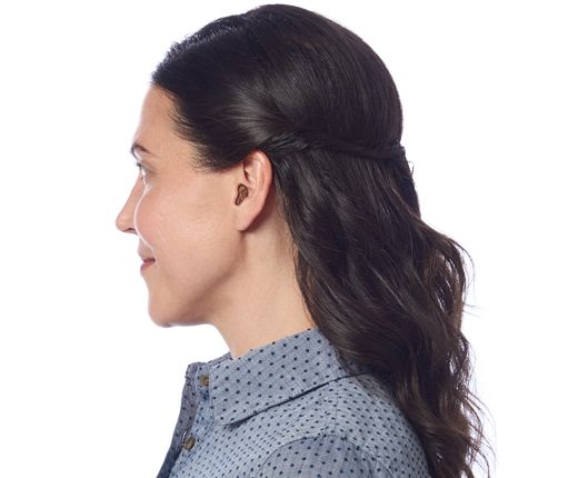 Woman with dark hair in a half-updo, wearing a blue patterned shirt, smiles in profile.