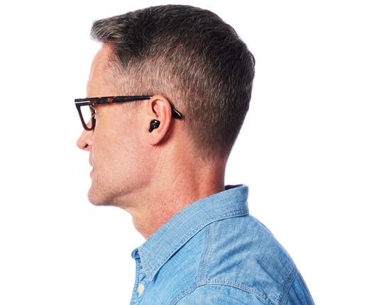 Man wearing glasses and a blue shirt, with earbuds in his ears.