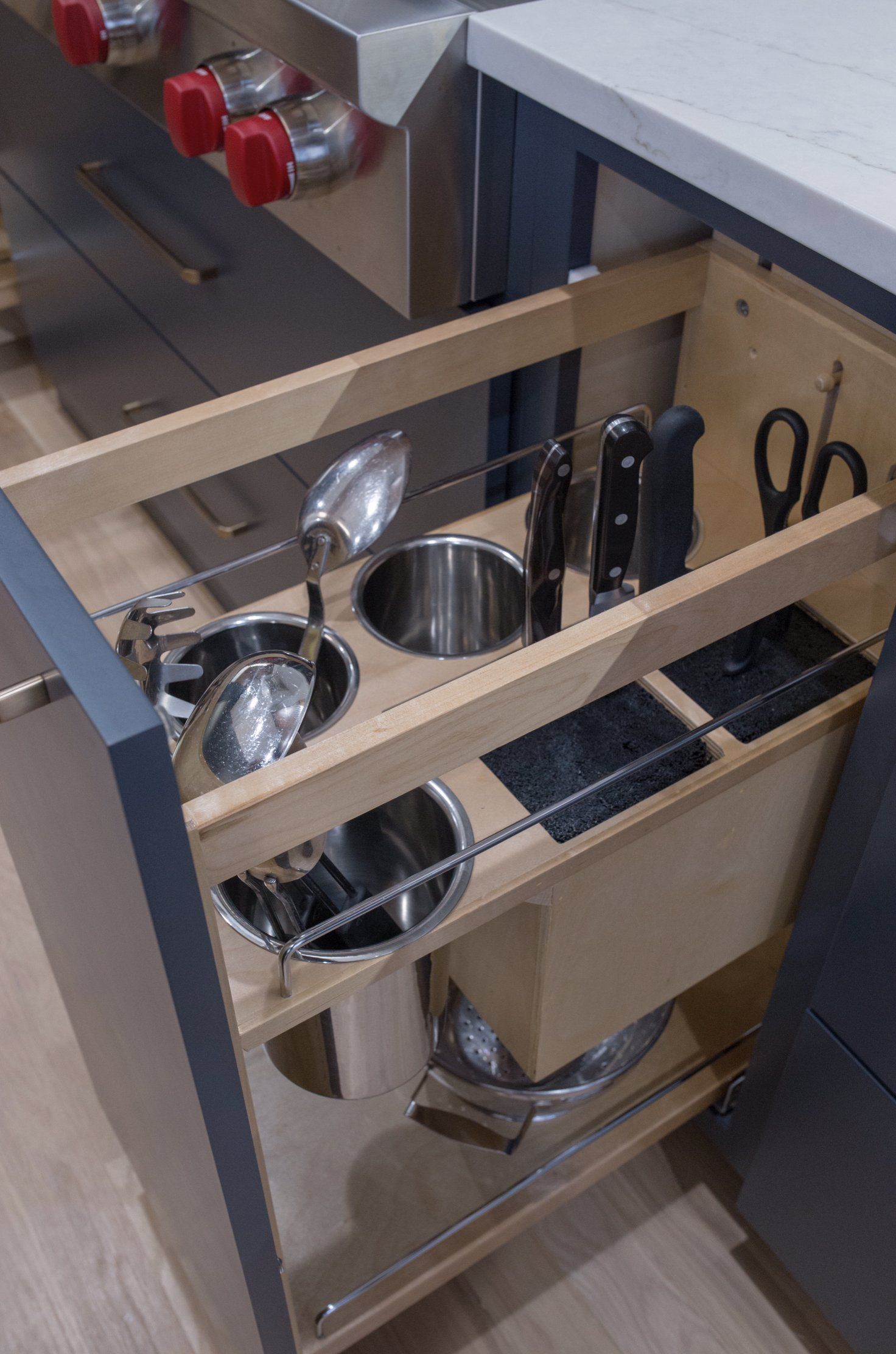 A kitchen drawer filled with pots and pans and knives.