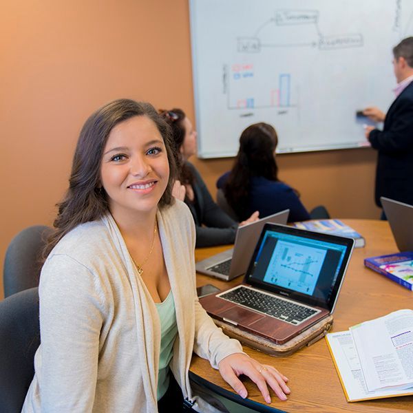 A woman sits at a table with a laptop on it