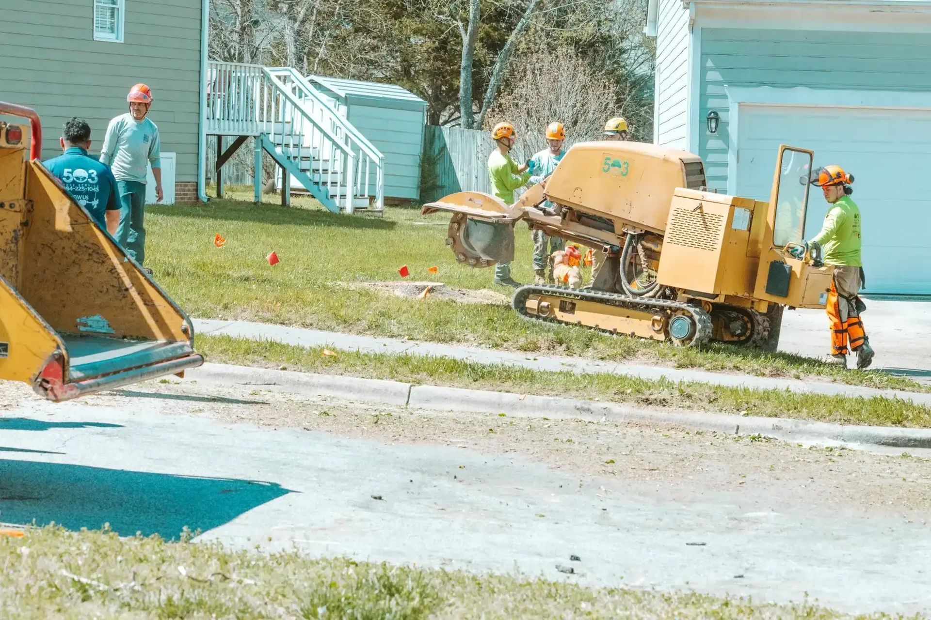 A group of men are working on a tree stump removal machine.