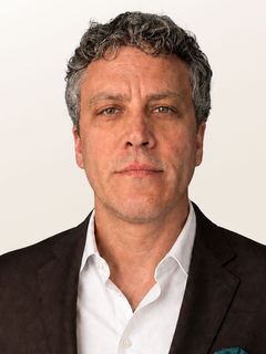 Head-and-shoulders portrait of a person in a white shirt against a plain light background.