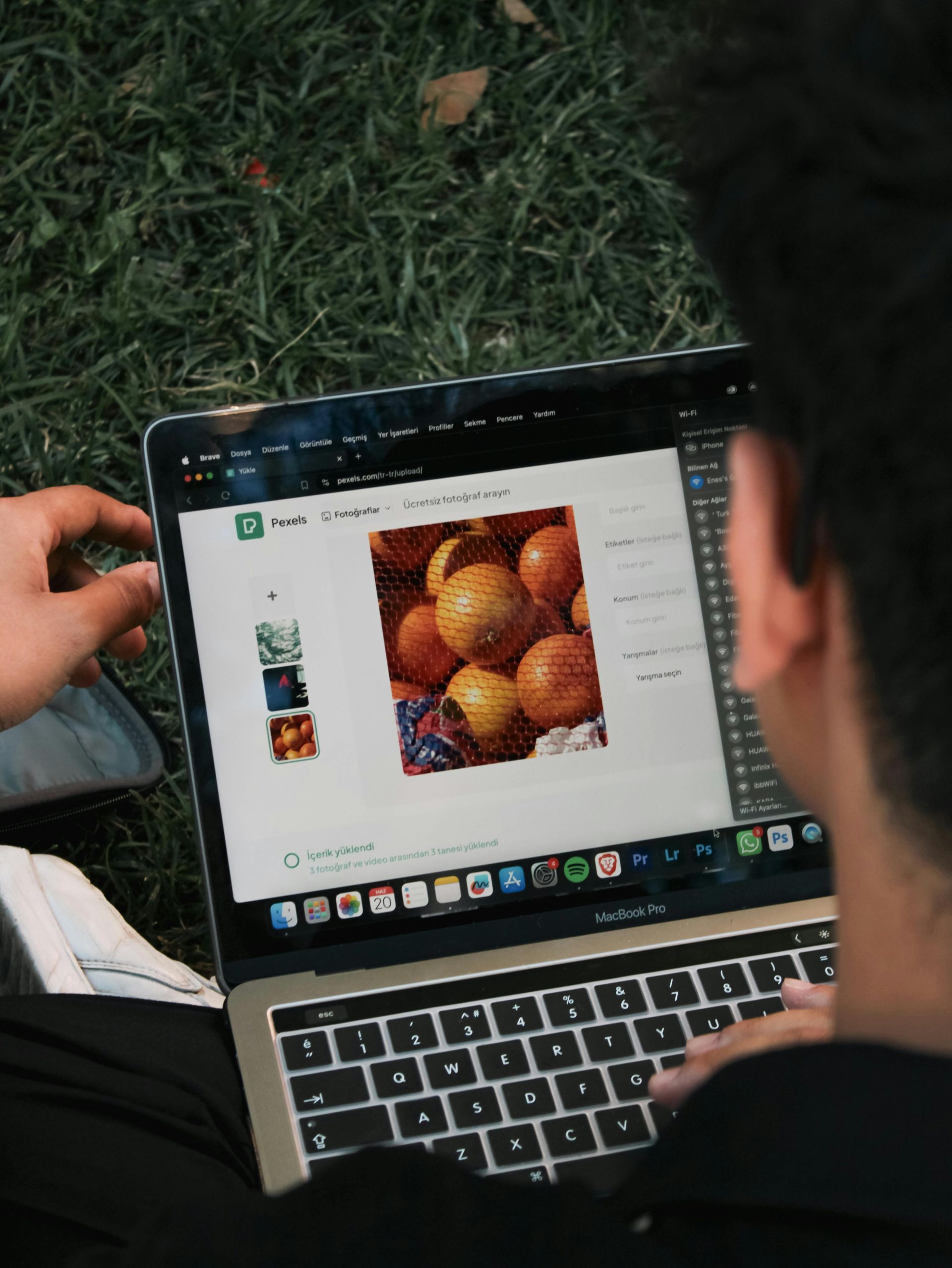Person using a laptop outdoors, viewing a webpage with photos of oranges and other fruit.