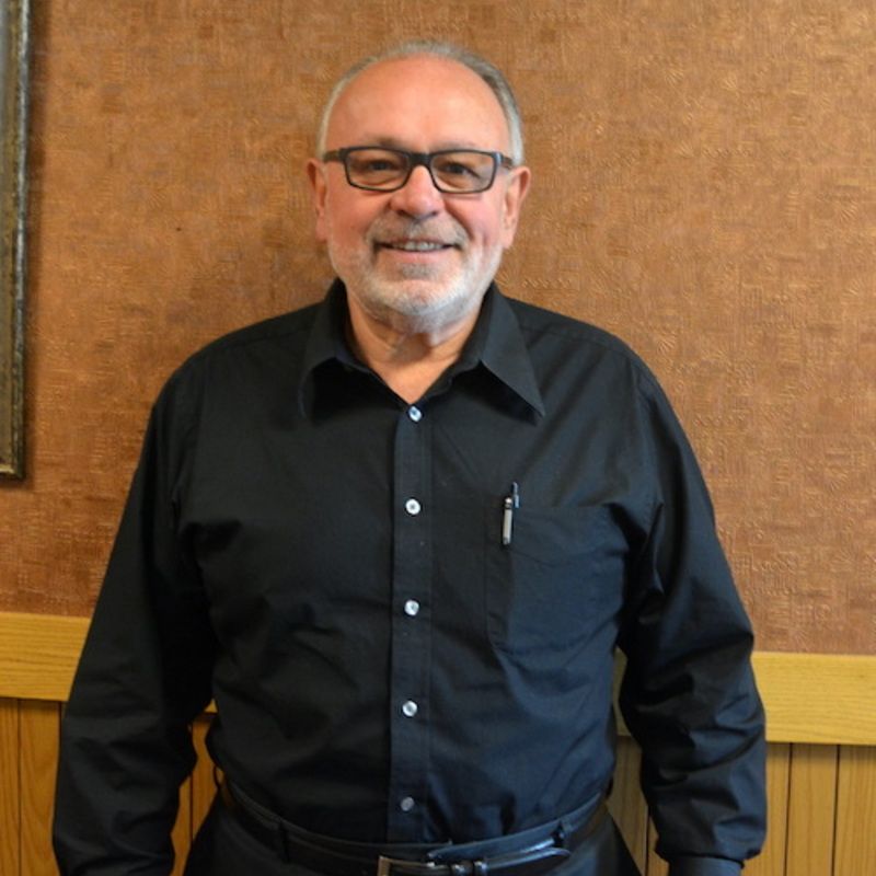 A bald man with glasses and a beard is smiling for the camera.