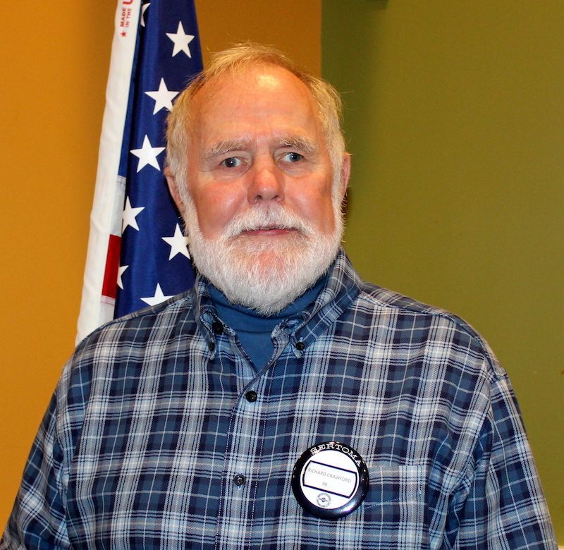 A bald man with glasses and a beard is smiling for the camera.