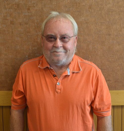 A bald man with glasses and a beard is smiling for the camera.