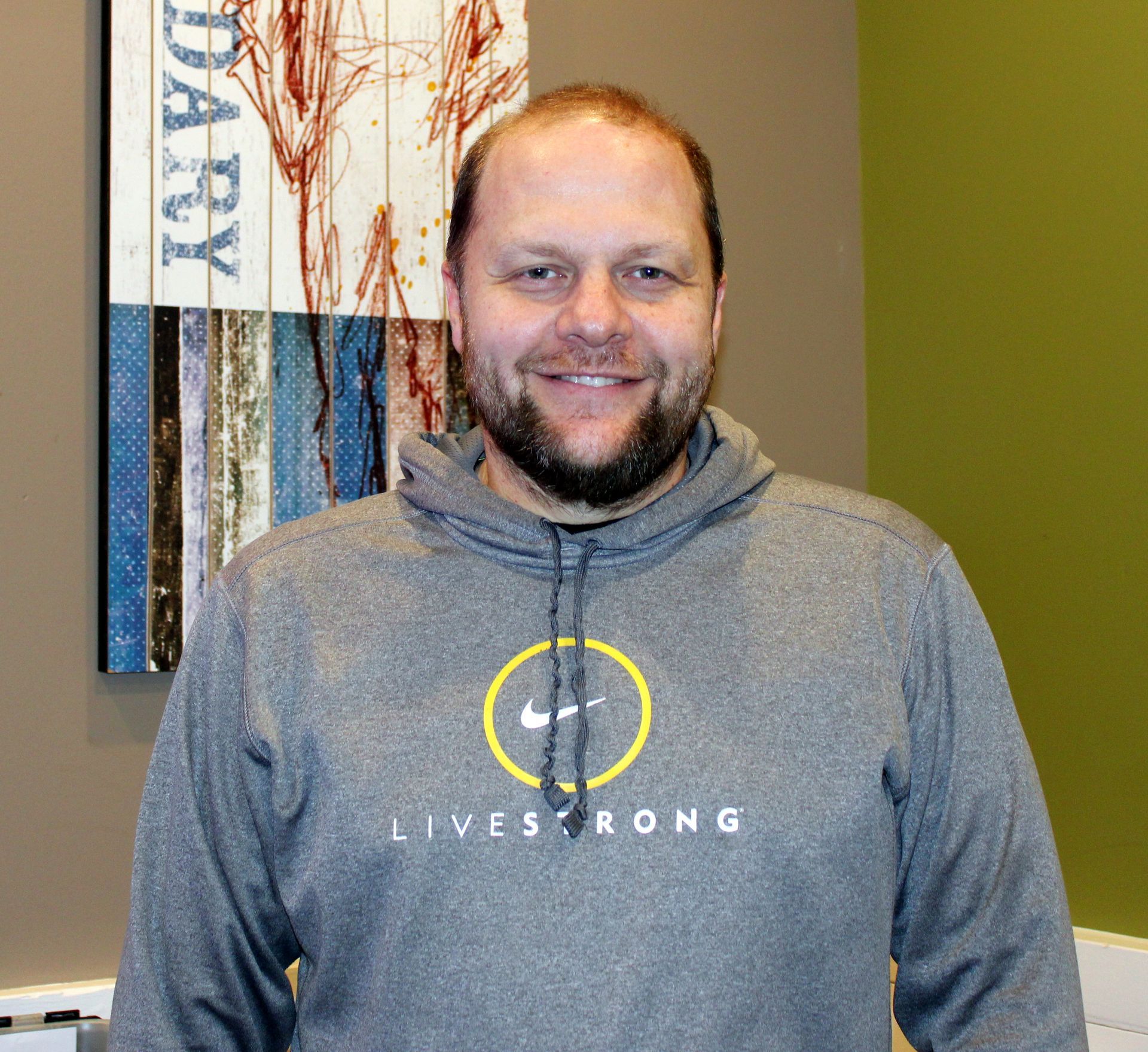 A bald man with glasses and a beard is smiling for the camera.