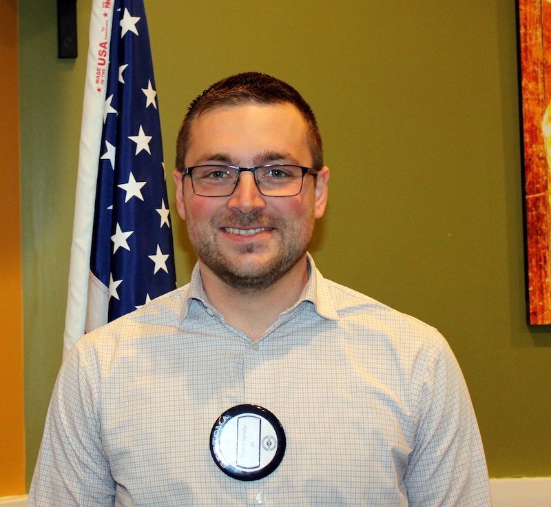 A bald man with glasses and a beard is smiling for the camera.