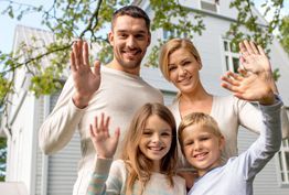 A family is waving their hands in front of a house.