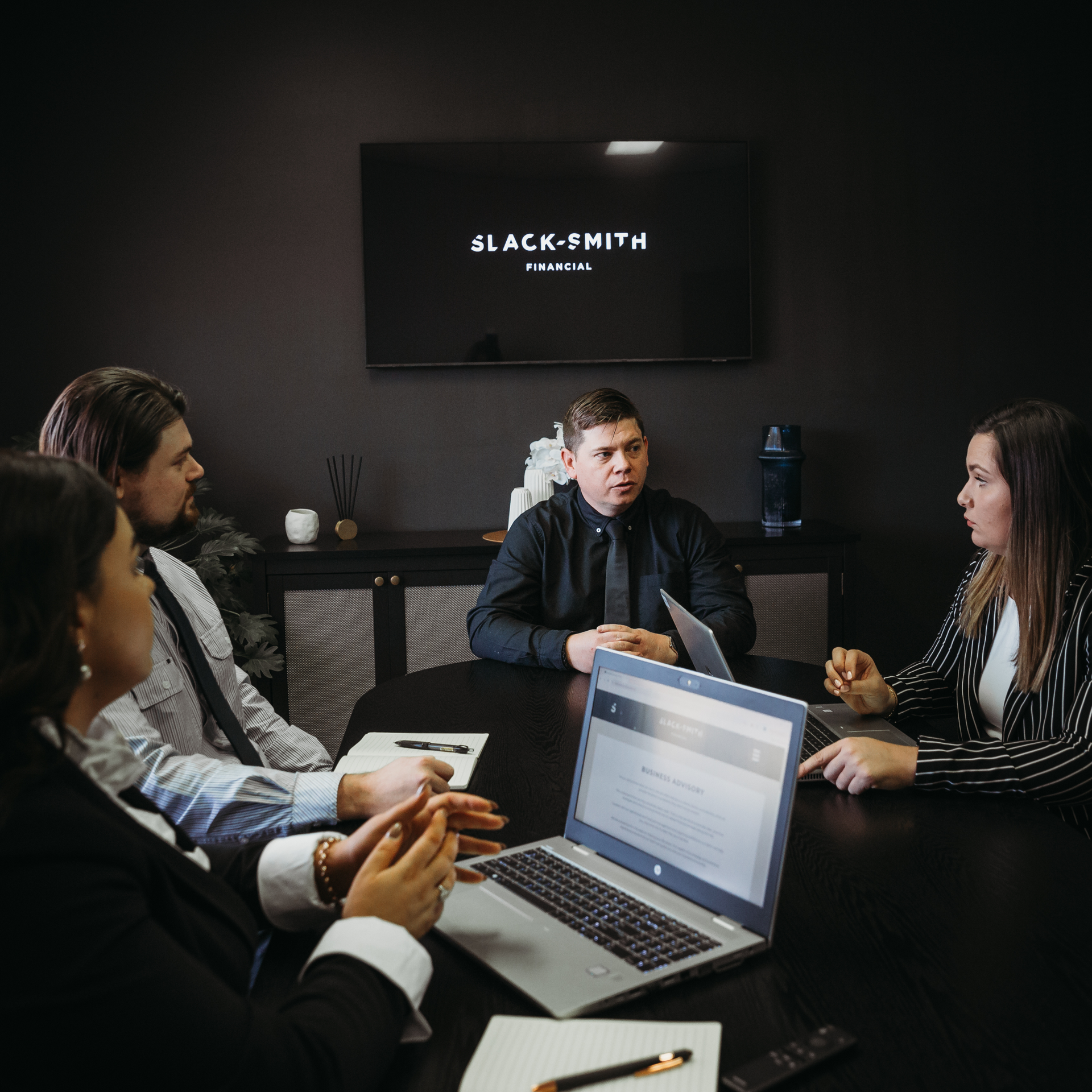A Group Of People Are Sitting Around A Table With Laptops — Slack-Smith Partners in Tamworth, NSW