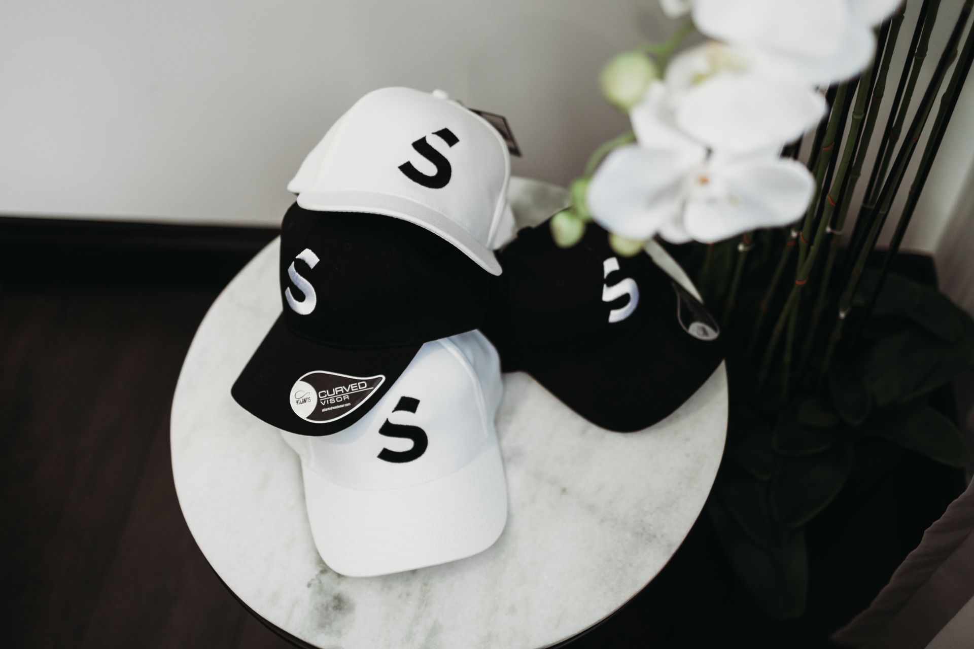 Four baseball caps, two black and two white, stacked on a marble-topped table — Slack-Smith Partners in Melbourne, NSW 