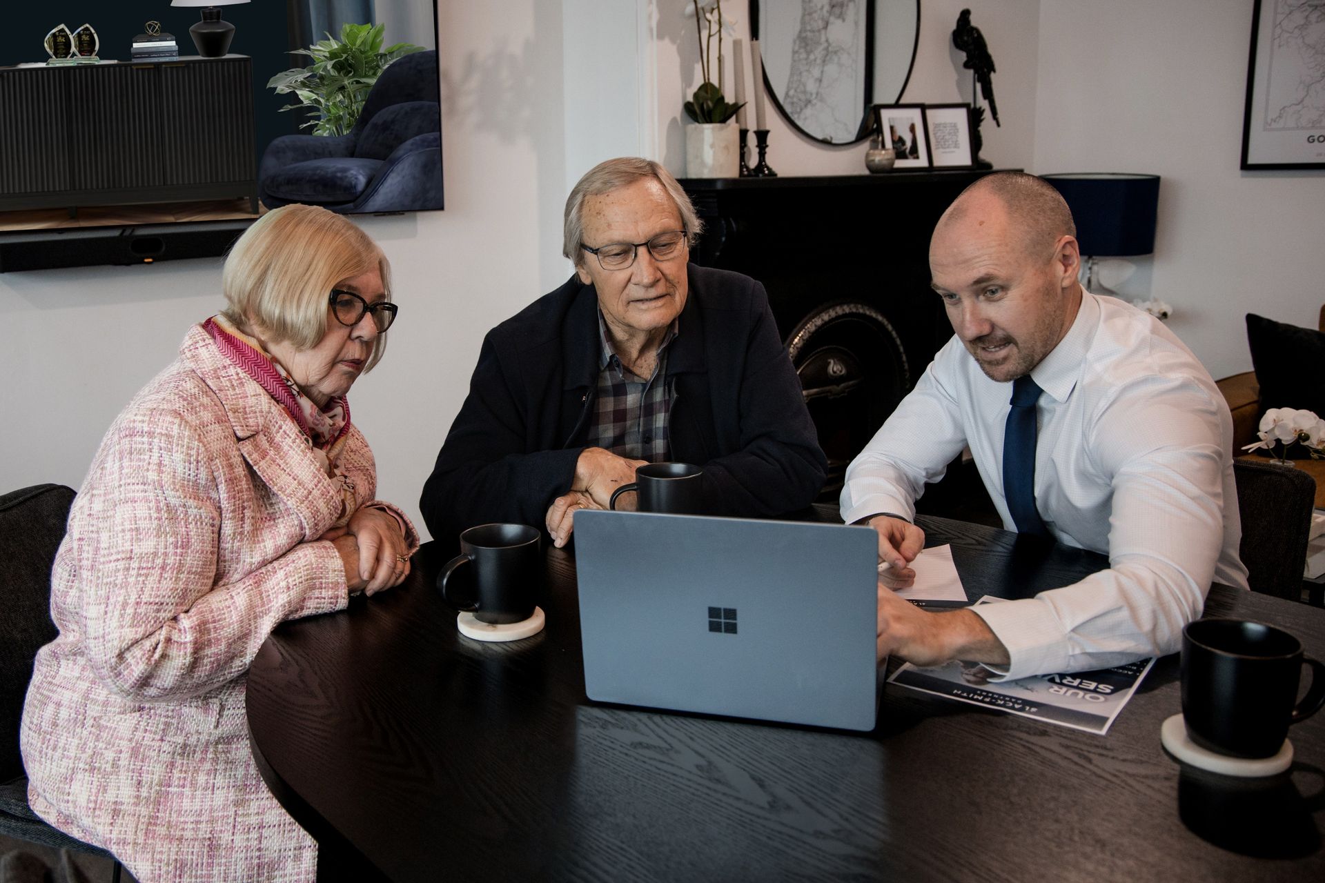 Older Couple and Advisor Looking at a Laptop, Discussing Documents at a Table — Slack-Smith Partners in Tamworth, NSW