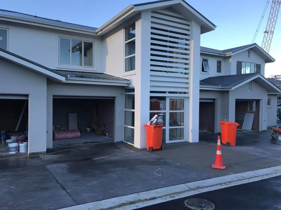 New townhouses under construction, with open garages, grey exteriors, and orange trash cans. New townhouses under construction, with open garages, grey exteriors, and orange trash cans.
