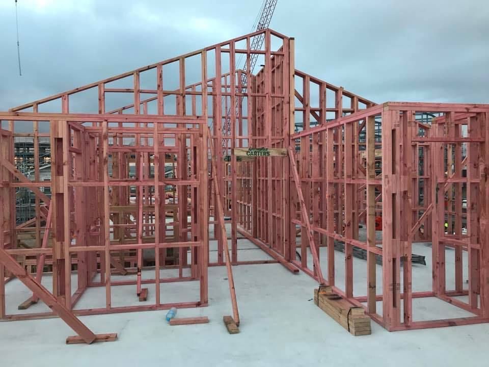 Wooden framework of a building under construction against a cloudy sky.