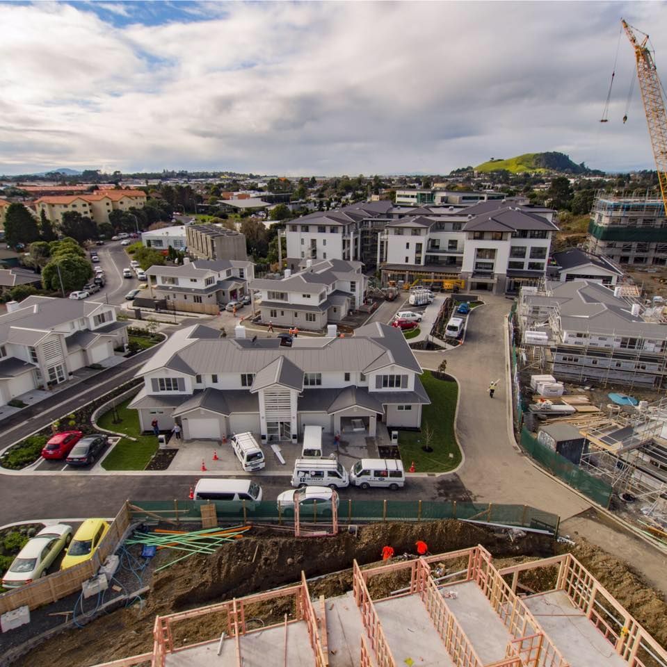 Aerial view of a suburban construction site with newly built townhouses and ongoing building work.