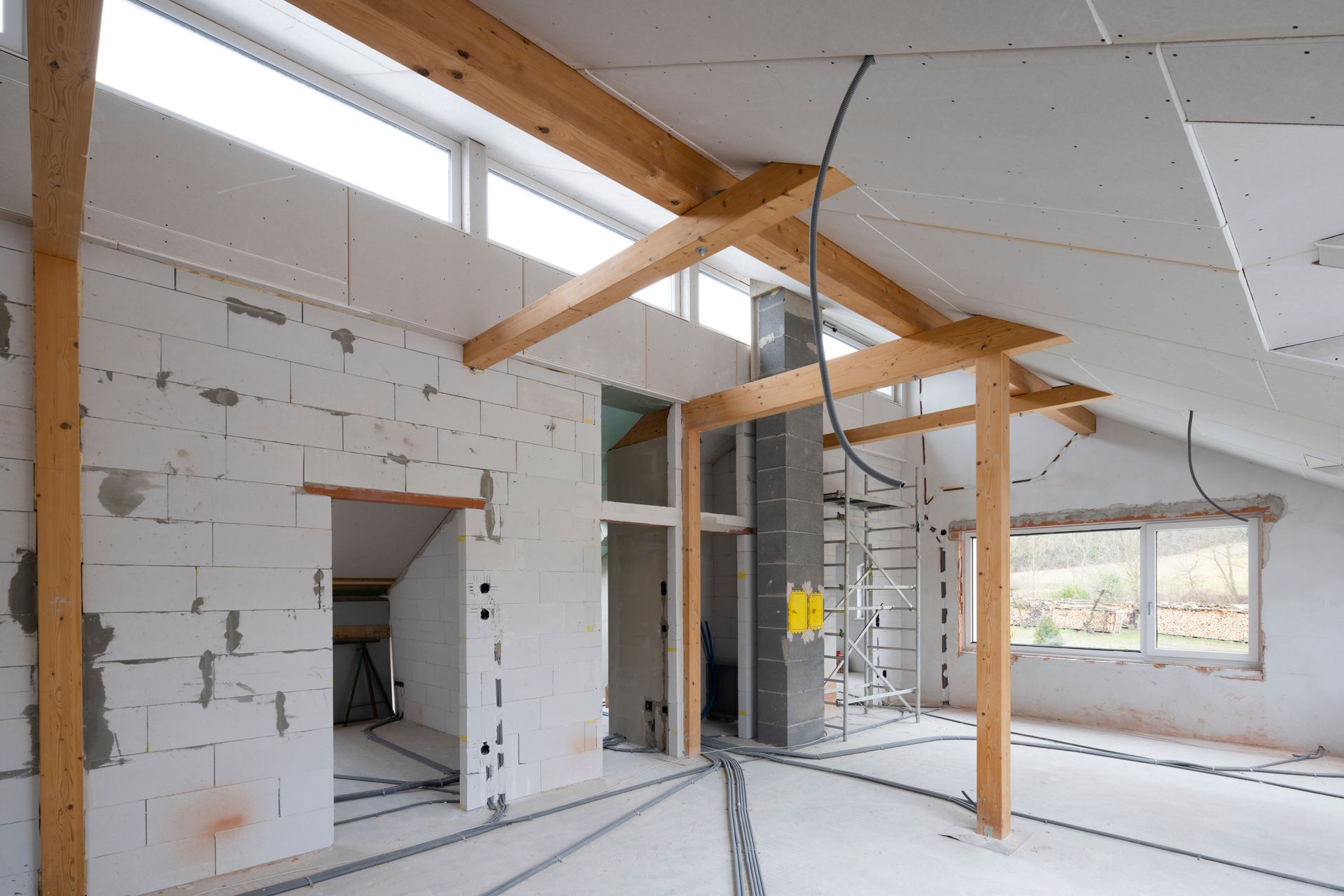 Interior of a building under construction, showing exposed wooden beams, concrete blocks, and wiring.