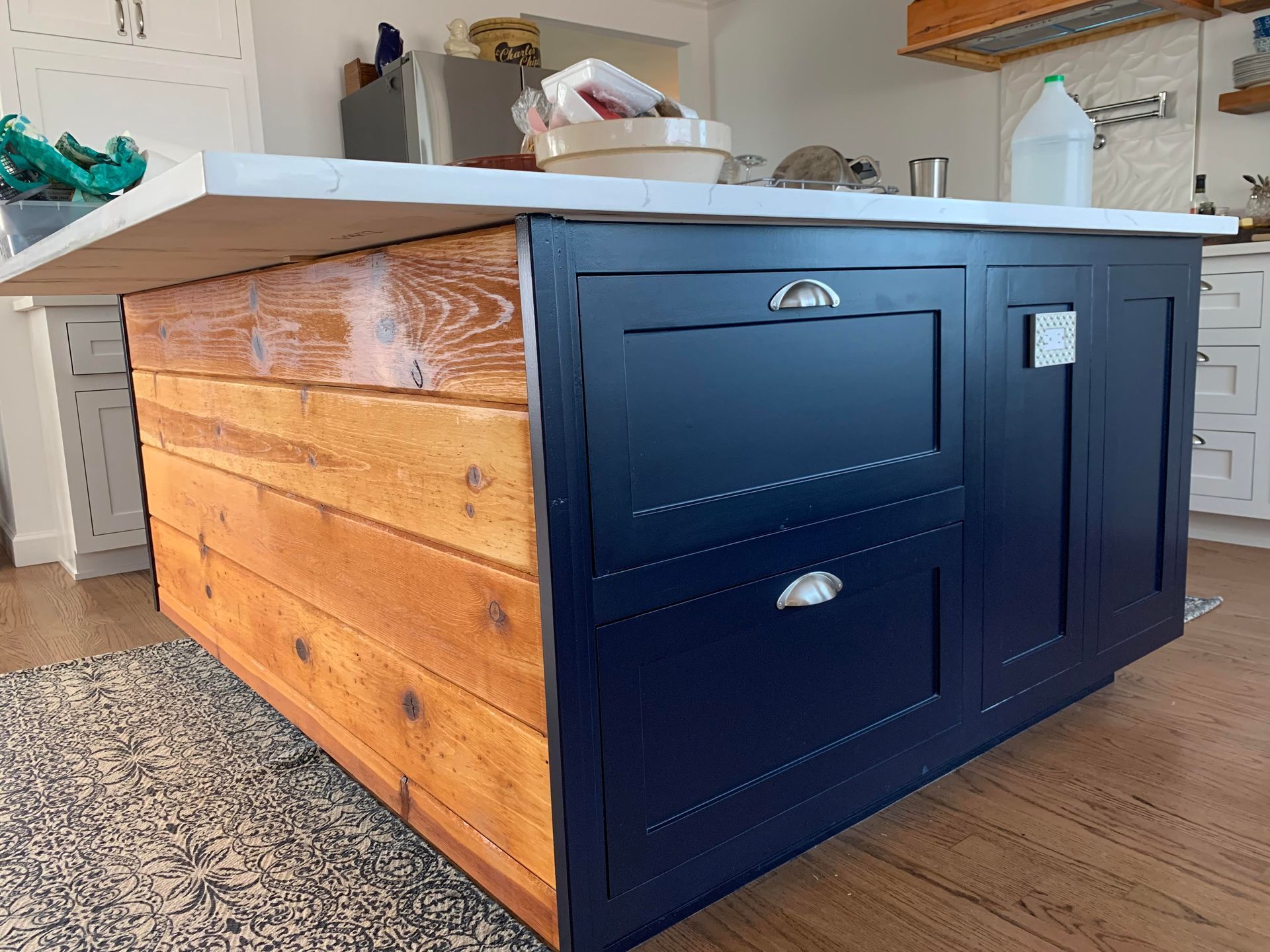 A kitchen island with blue cabinets and wooden trim.