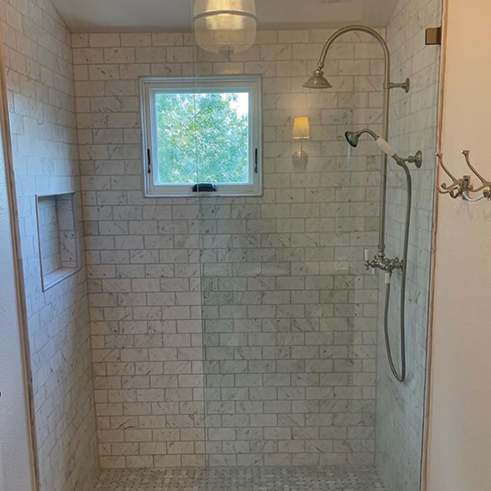A shower with white brick walls and a window
