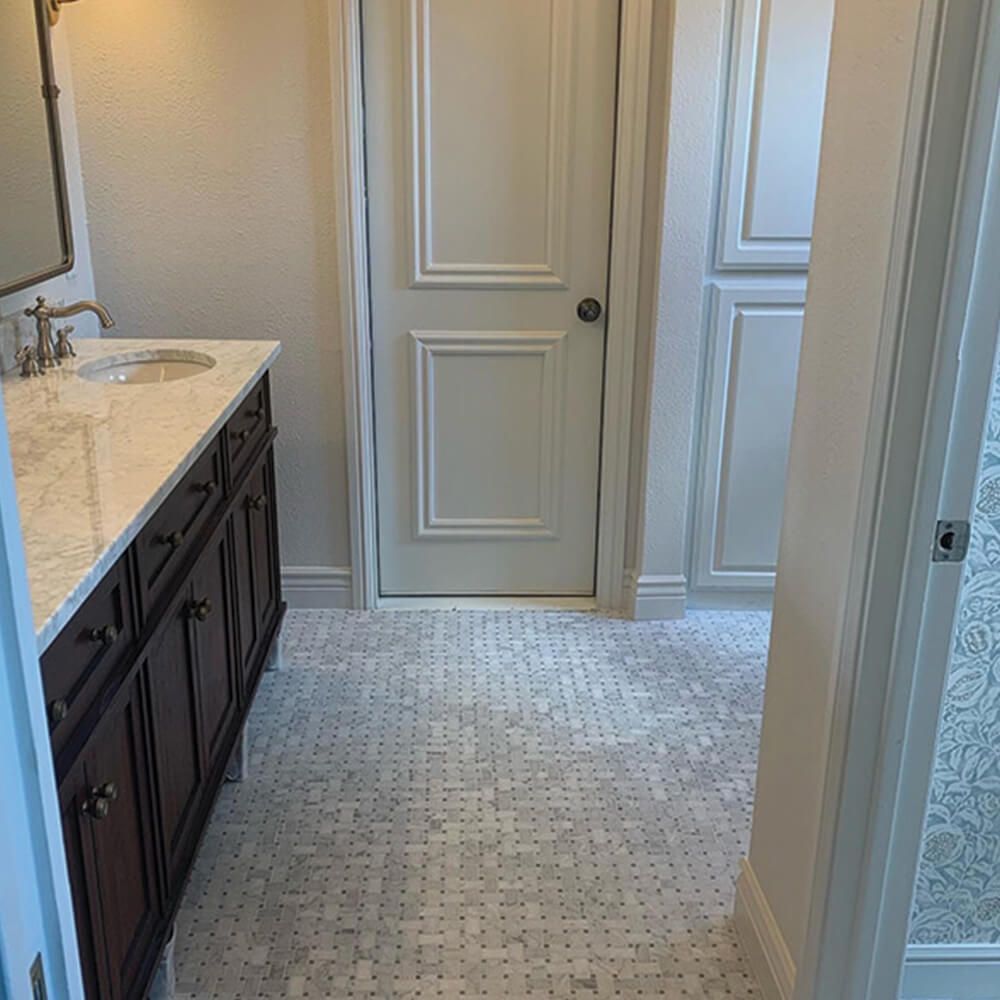 A bathroom with a sink , mirror and door.