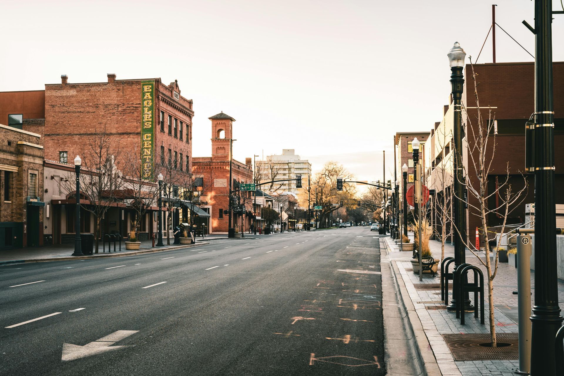 Empty downtown street lined with brick buildings and storefronts at dusk