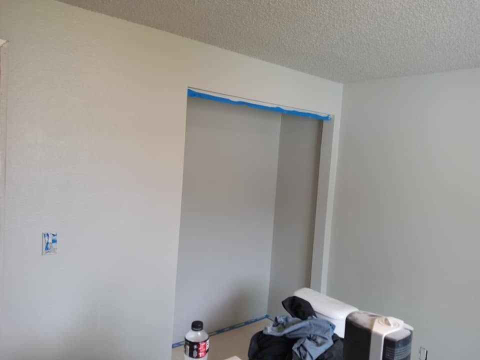 Partially finished room with a closet opening covered in blue painter’s tape and a bed in the foreground