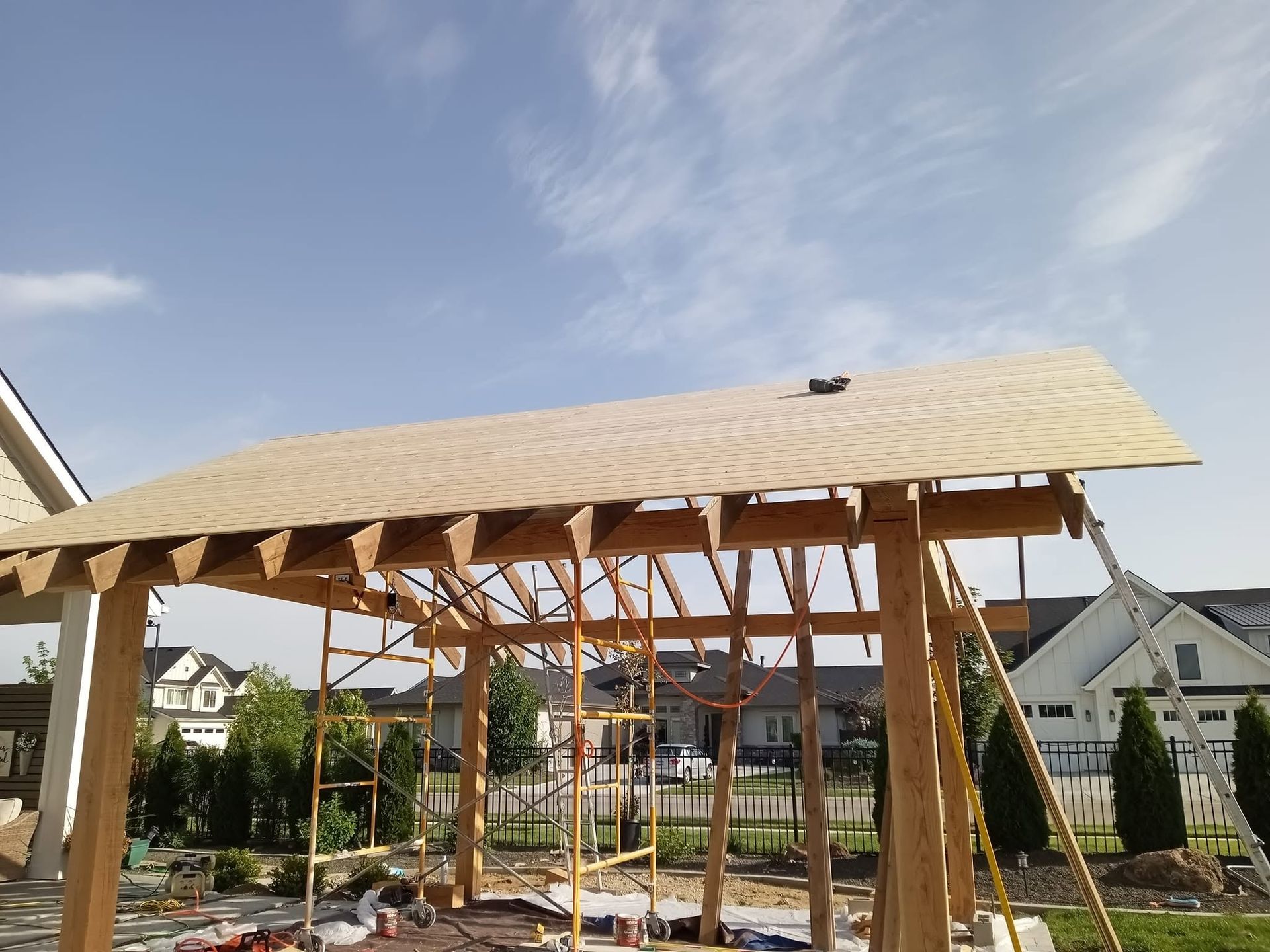 Partially built wooden gazebo frame with a pale roof under construction in a residential yard