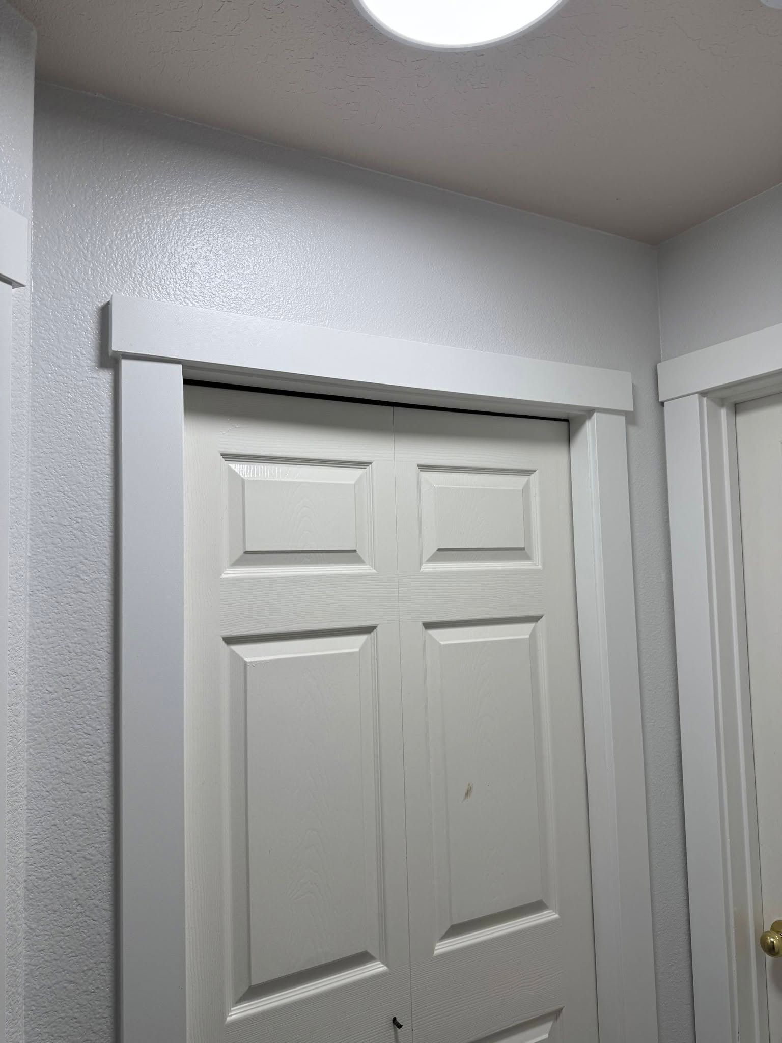 White closet doors with a gray frame in a hallway under a ceiling light