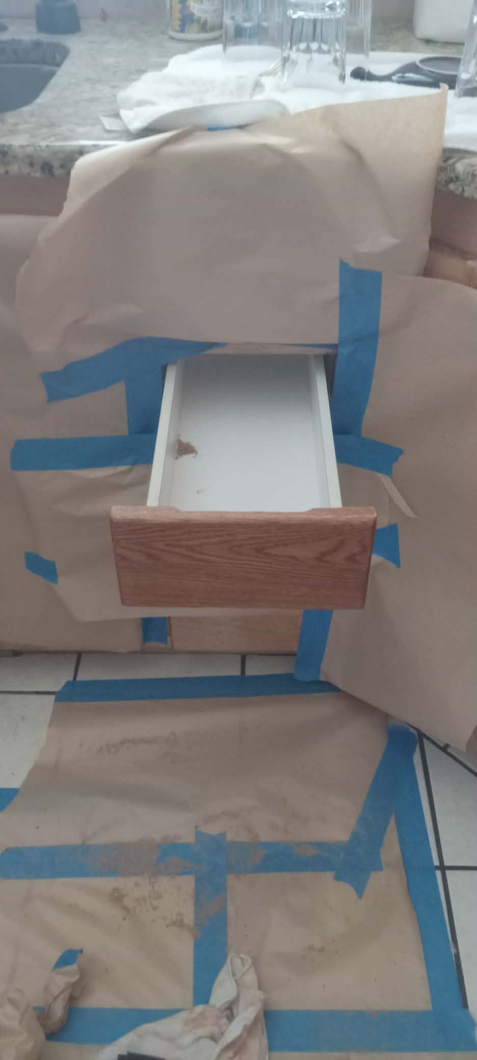 Blue-taped cardboard model with a white tray and fabric covering in a workshop-like setting