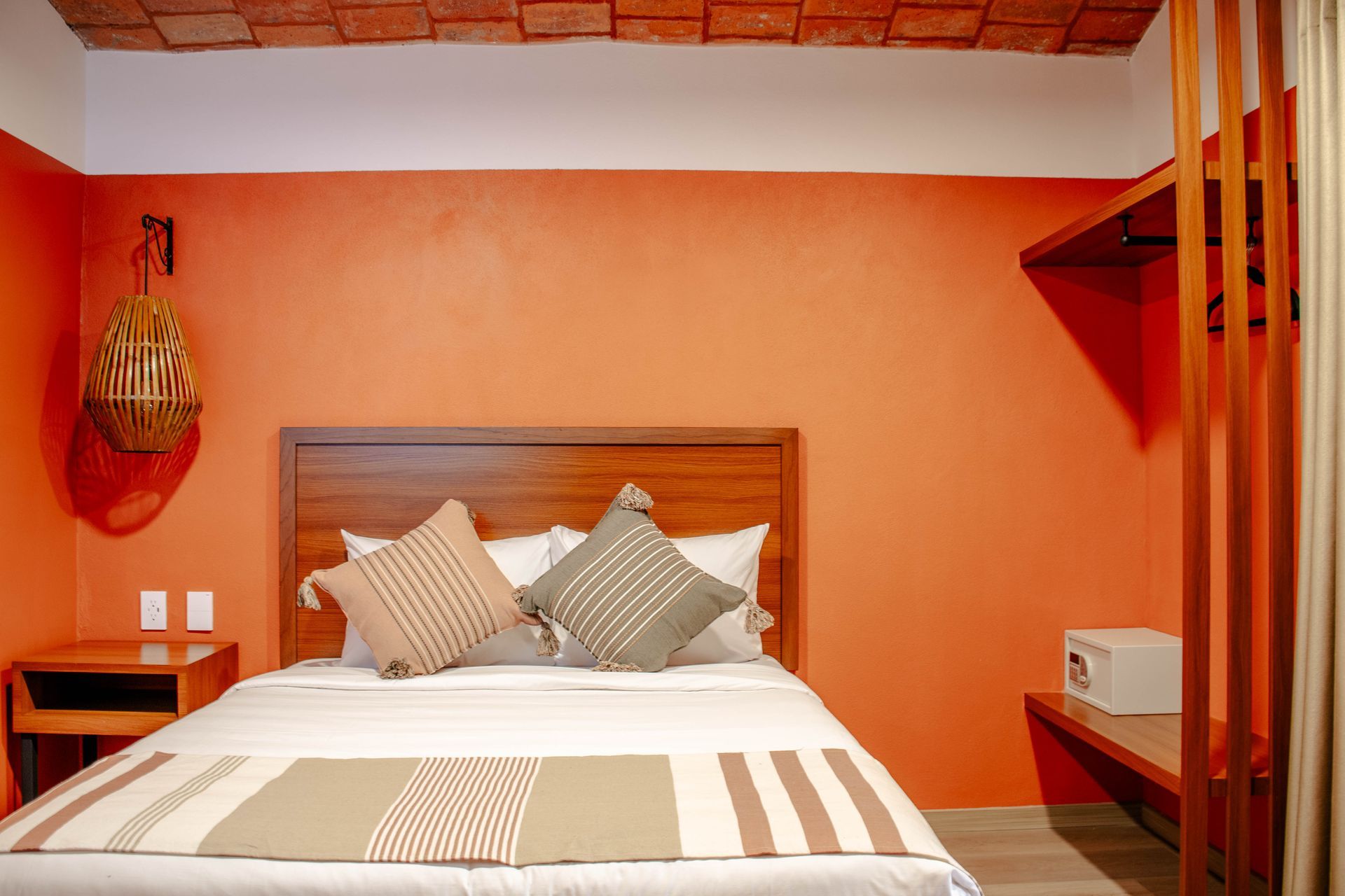 Dormitorio naranja con cama de madera, ropa de cama a rayas y decoración minimalista