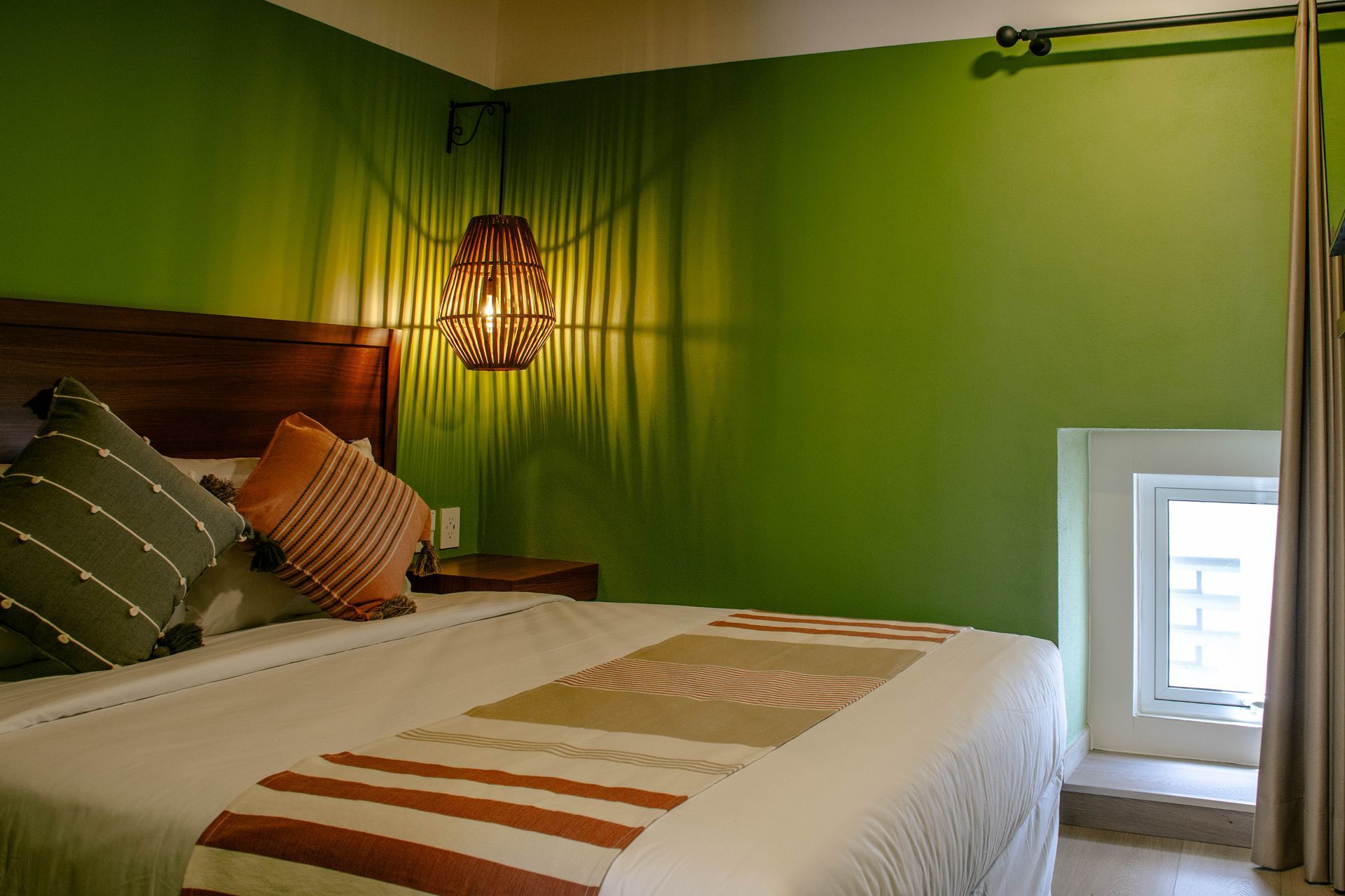 Dormitorio acogedor con paredes verdes, una cama bien hecha y una lámpara colgante sobre el cabecero
