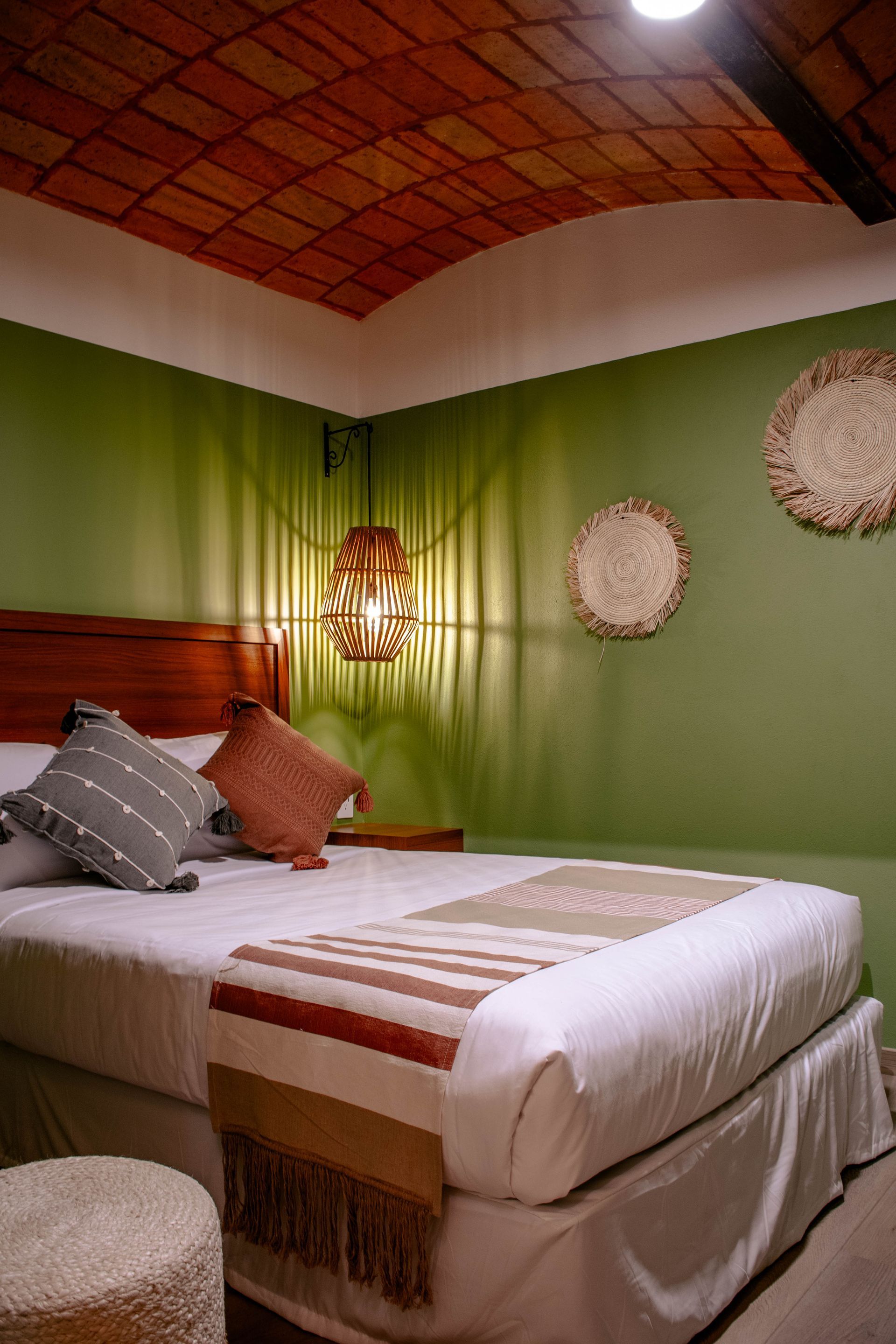 Dormitorio acogedor con paredes verdes, cabecero de madera, ropa de cama estampada y decoración mural tejida