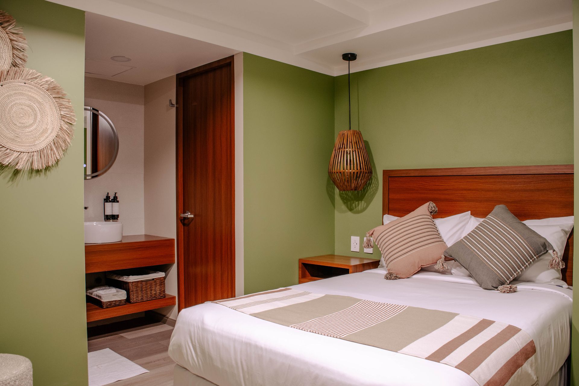 Acogedor dormitorio con paredes verdes, cama de madera y zona de tocador contigua al baño
