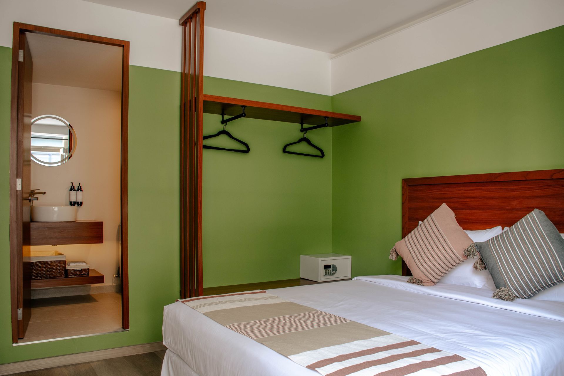 Dormitorio moderno con paredes verdes, cama, estante de pared y espejo junto a una puerta