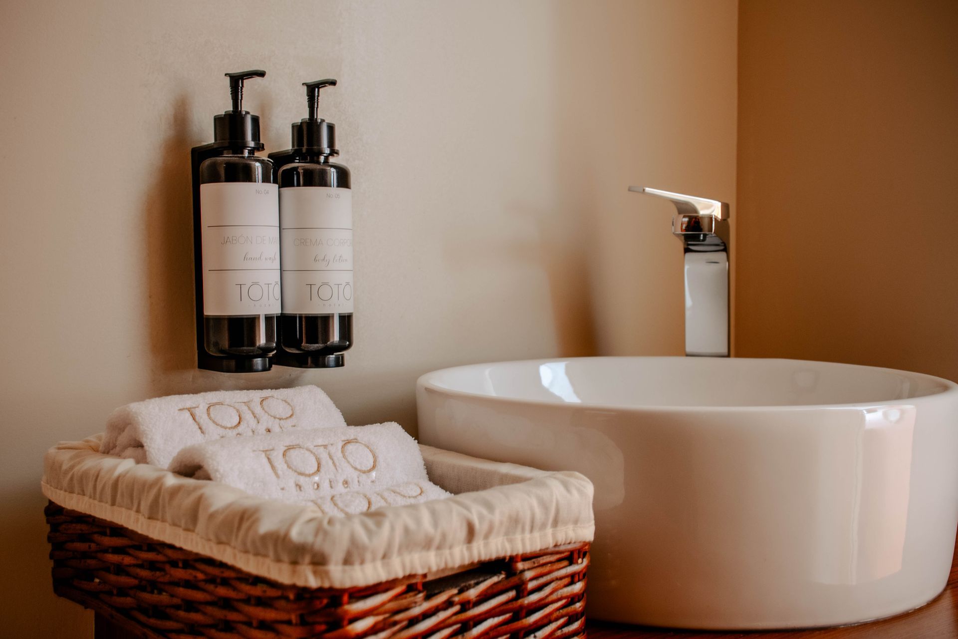 Encimera de baño de spa con lavabo, dispensadores de jabón y una cesta de toallas