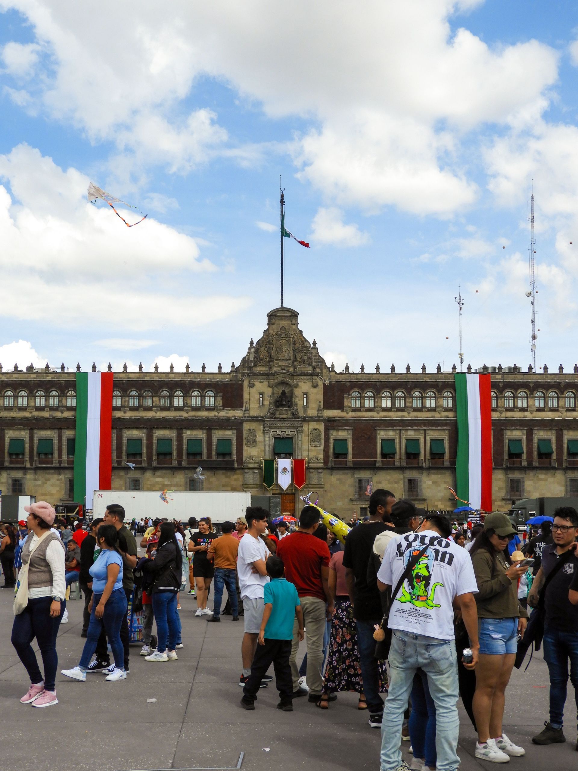 Una multitud se congregó en una plaza frente a un edificio histórico con banderas mexicanas ondeando en su fachada.