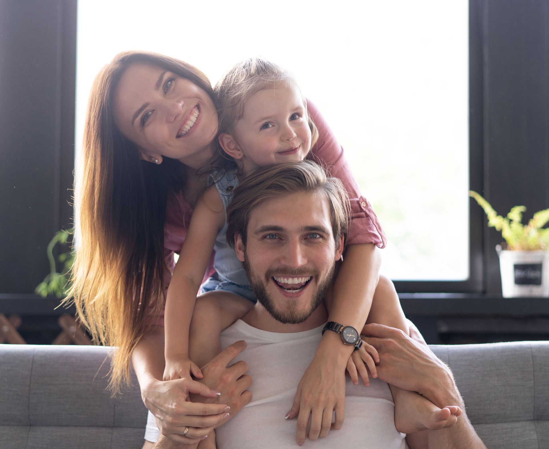 A man and woman are sitting on a couch with a child on their shoulders.